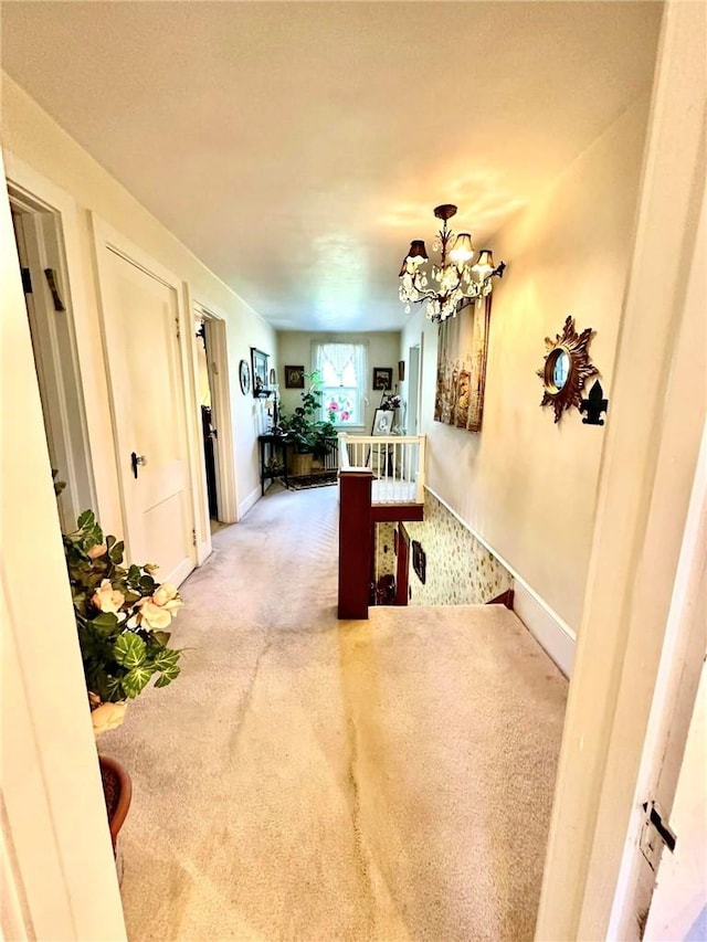 hallway with carpet floors and a chandelier