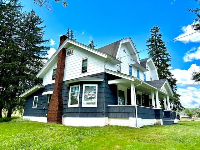 view of home's exterior featuring a lawn, a chimney, and a porch