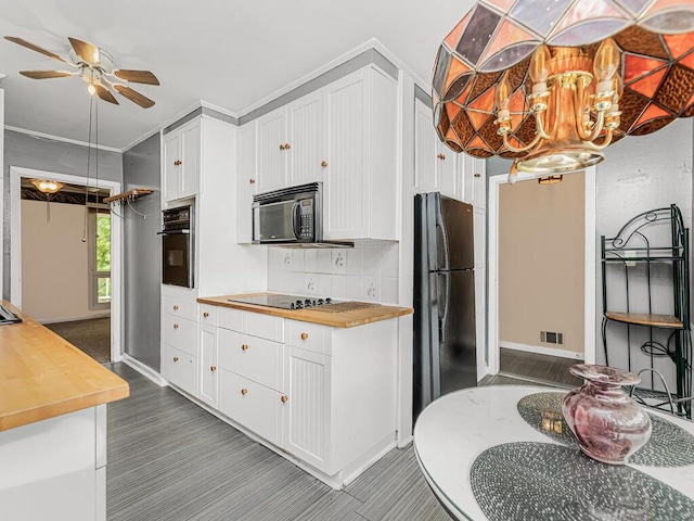 kitchen featuring white cabinets, ceiling fan with notable chandelier, black appliances, decorative backsplash, and butcher block countertops