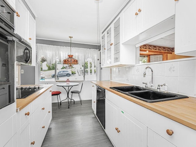 kitchen featuring pendant lighting, dark wood-type flooring, white cabinets, black appliances, and sink