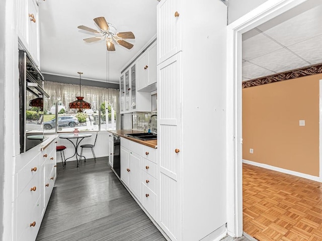 kitchen with white cabinetry, sink, parquet flooring, decorative light fixtures, and black appliances