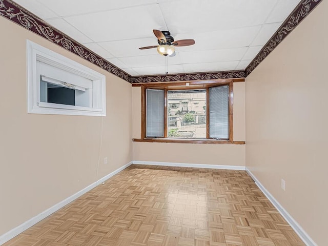unfurnished room with a paneled ceiling, light parquet floors, and ceiling fan