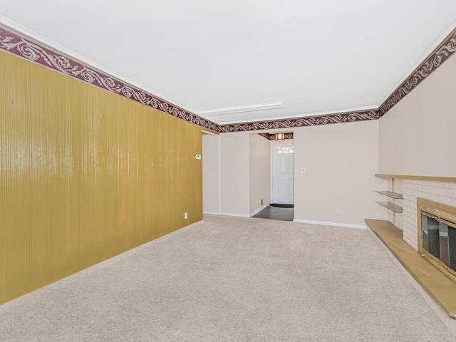unfurnished living room with carpet floors, a brick fireplace, and ornamental molding