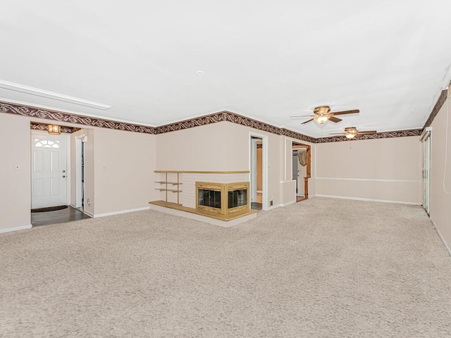 unfurnished living room featuring carpet flooring, a brick fireplace, ceiling fan, and crown molding