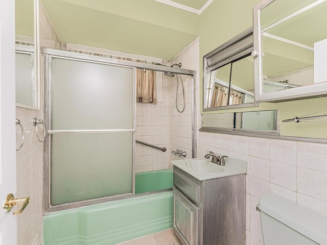 full bathroom with shower / bath combination with glass door, vanity, toilet, and tile walls