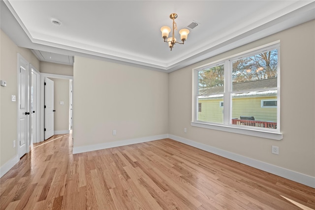 spare room featuring an inviting chandelier and light hardwood / wood-style floors