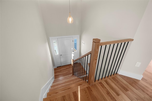 stairs featuring hardwood / wood-style floors and a high ceiling