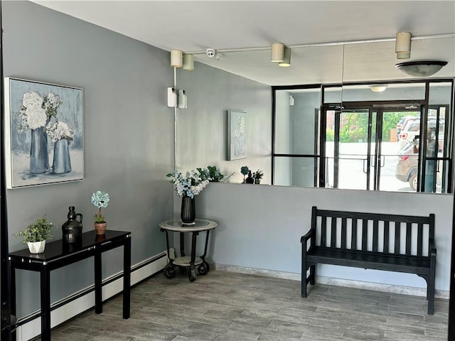 corridor with hardwood / wood-style floors and a baseboard heating unit