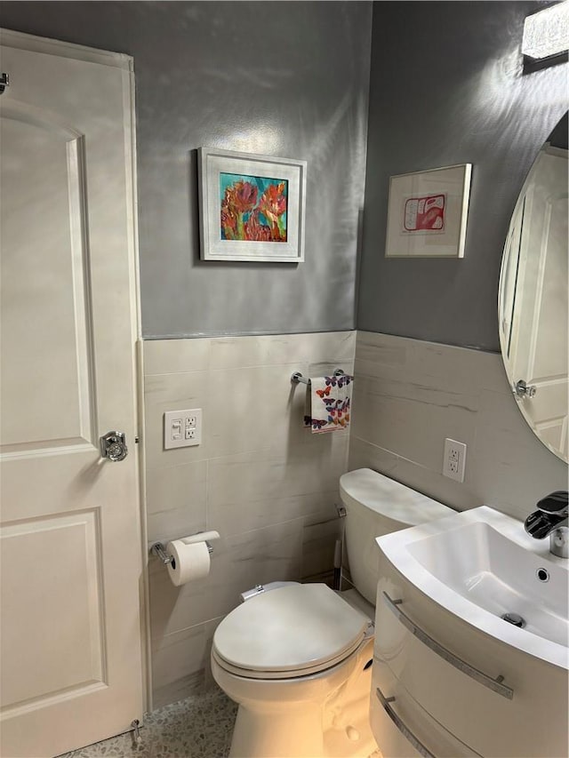 bathroom featuring vanity, toilet, and tile walls