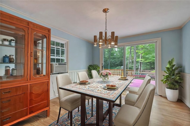 dining room featuring light wood-type flooring, ornamental molding, and an inviting chandelier