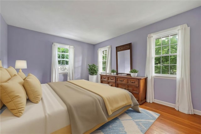 bedroom with multiple windows and light hardwood / wood-style floors