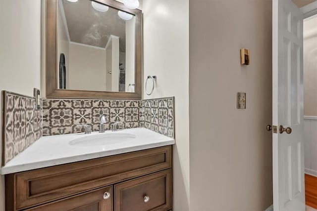 bathroom featuring hardwood / wood-style flooring, vanity, ornamental molding, and backsplash