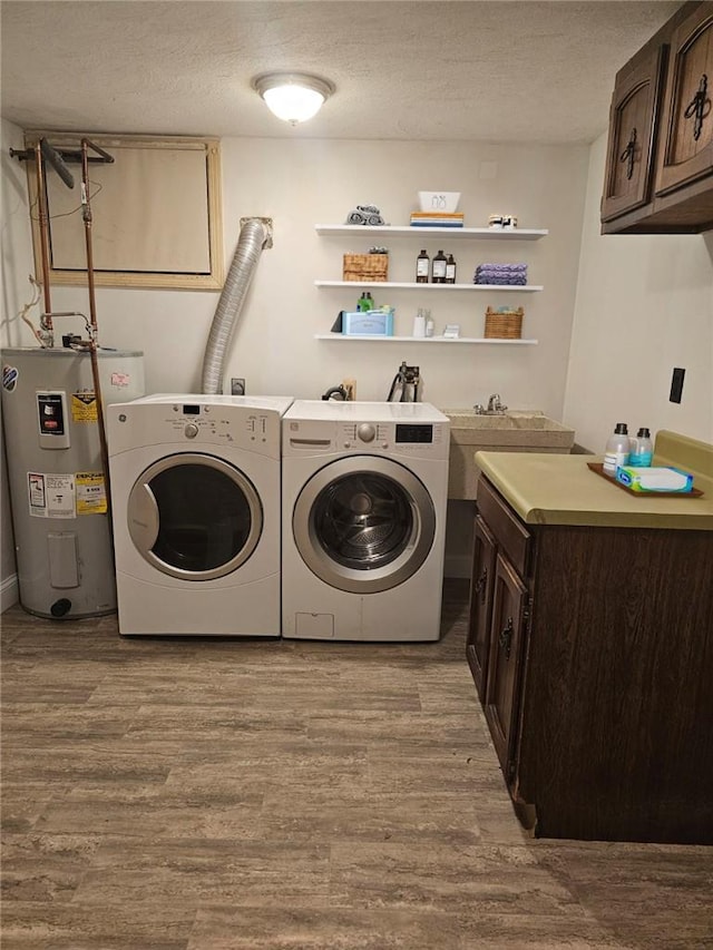 washroom with cabinets, electric water heater, washing machine and dryer, light wood-type flooring, and a textured ceiling