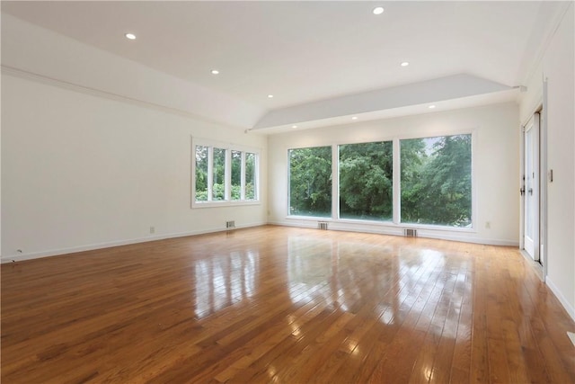 empty room with light wood-type flooring and vaulted ceiling