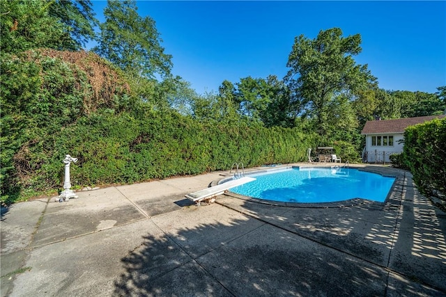 view of swimming pool with a diving board and a patio