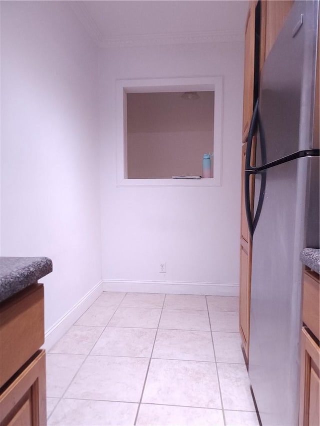 interior space with stainless steel refrigerator, crown molding, and light tile patterned flooring