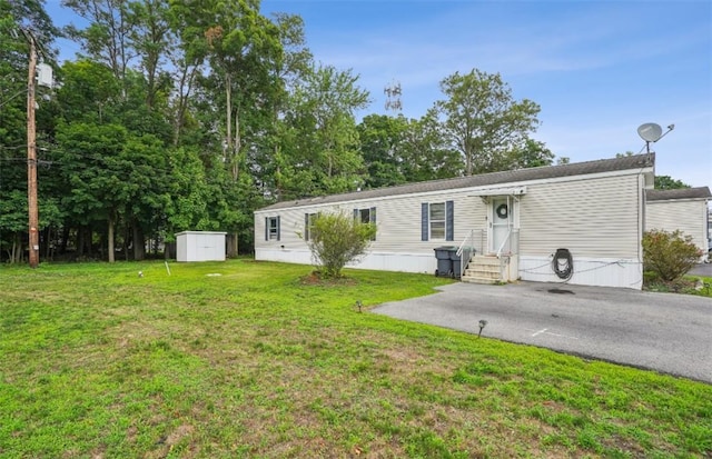 manufactured / mobile home featuring a shed and a front lawn