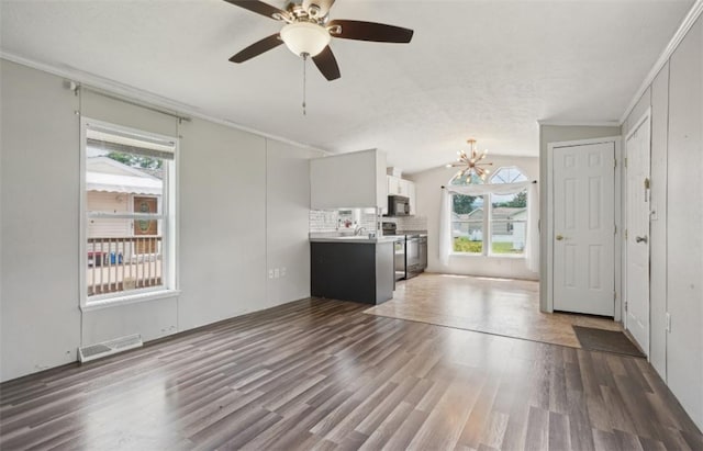 unfurnished living room with plenty of natural light, ceiling fan with notable chandelier, dark wood-type flooring, and lofted ceiling