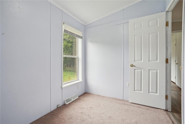 carpeted empty room featuring vaulted ceiling and ornamental molding