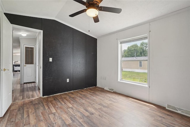 empty room featuring wood-type flooring, crown molding, ceiling fan, and lofted ceiling