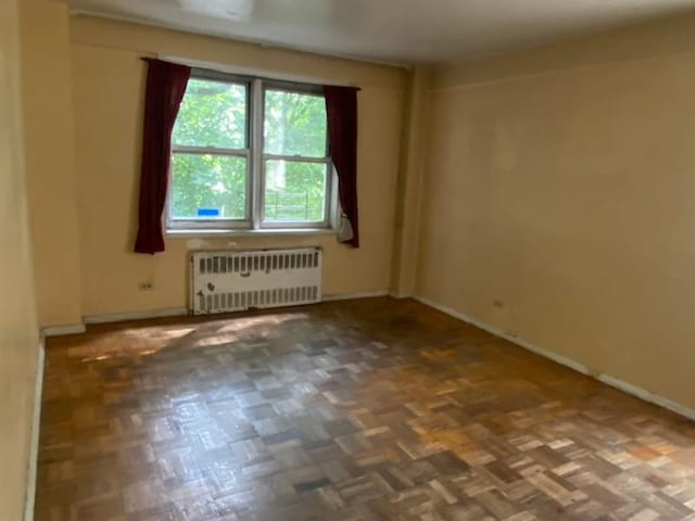 empty room featuring dark parquet floors and radiator