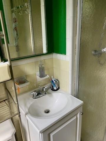 bathroom featuring vanity, toilet, and tile walls