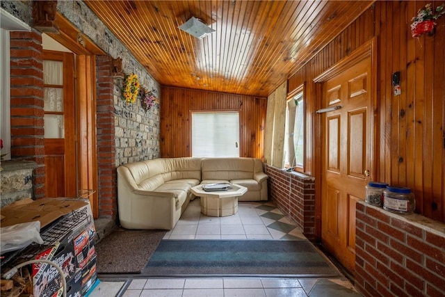 living area featuring light tile patterned floors, vaulted ceiling, wooden walls, and wood ceiling