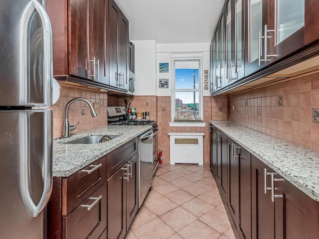 kitchen with light stone countertops, sink, light tile patterned flooring, and appliances with stainless steel finishes