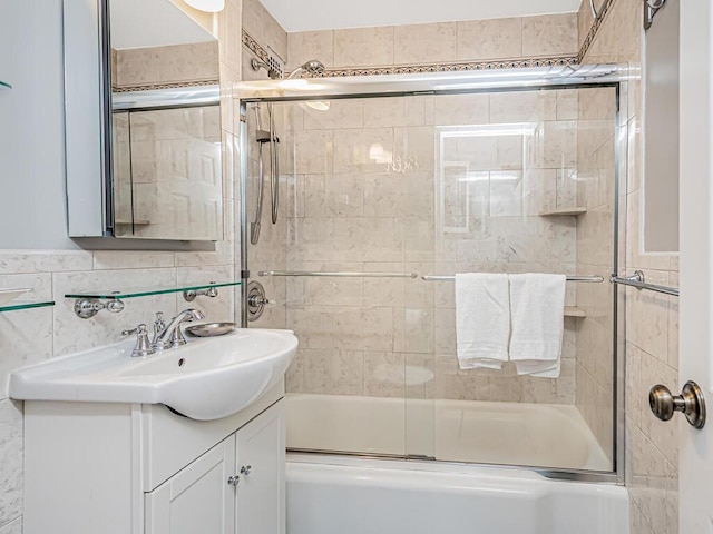 bathroom with combined bath / shower with glass door, vanity, and tile walls