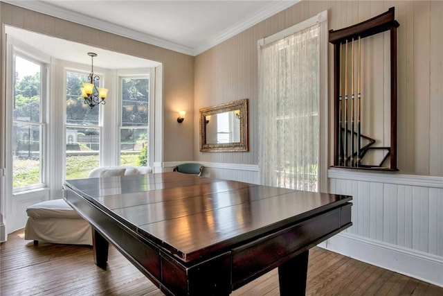 dining area with ornamental molding, plenty of natural light, hardwood / wood-style floors, and an inviting chandelier