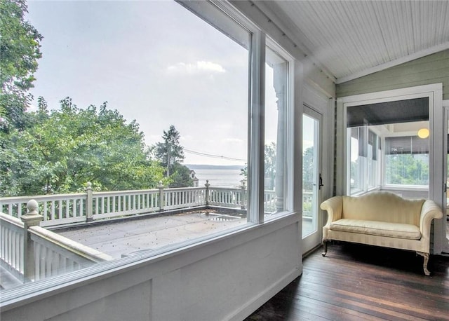 sunroom with lofted ceiling and a water view