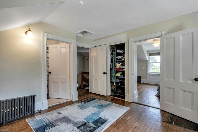 unfurnished bedroom with dark hardwood / wood-style flooring, radiator, lofted ceiling, and a closet