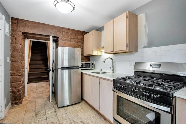 kitchen featuring stainless steel appliances, light brown cabinetry, sink, and decorative backsplash