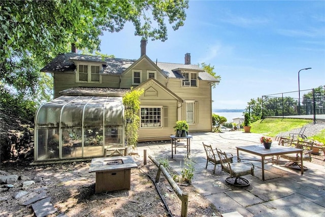 rear view of property with an outdoor fire pit, a patio area, and a sunroom