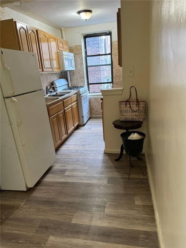 kitchen featuring light wood-type flooring, white appliances, backsplash, and sink