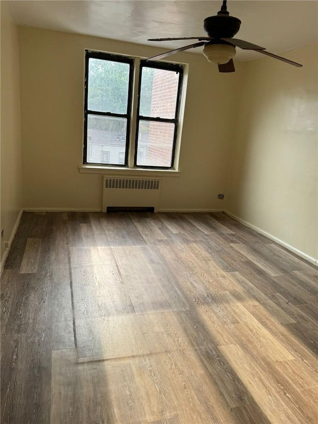 empty room featuring hardwood / wood-style floors, ceiling fan, and radiator