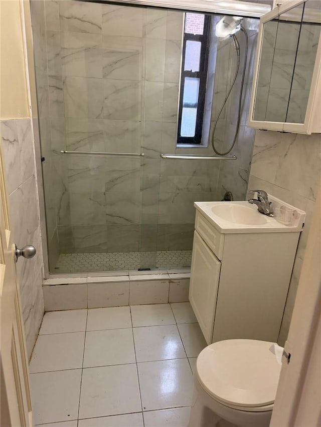 bathroom featuring vanity, toilet, a shower with door, and tile walls