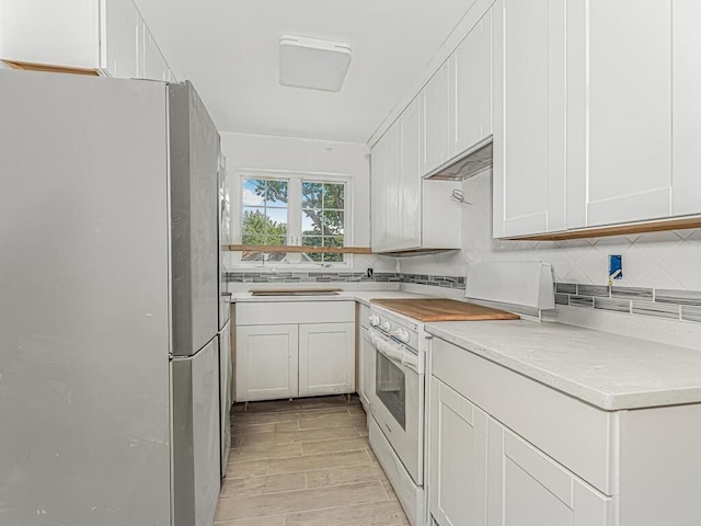 kitchen with stainless steel fridge, white electric range, and white cabinetry