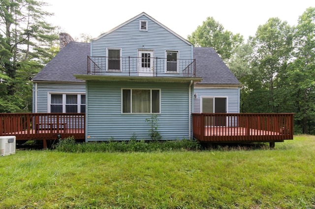 rear view of property with a lawn, a balcony, and a deck