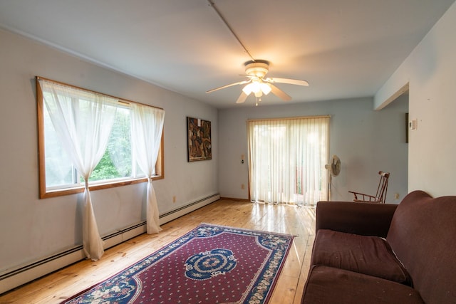 living room featuring ceiling fan, light hardwood / wood-style floors, and a baseboard heating unit