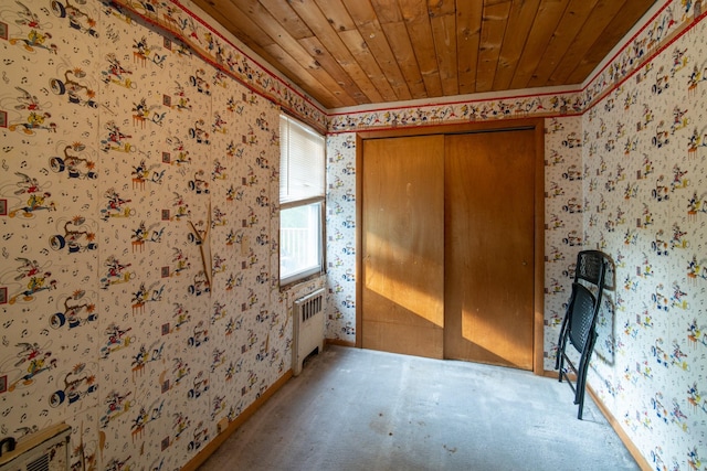 carpeted spare room with radiator heating unit and wood ceiling