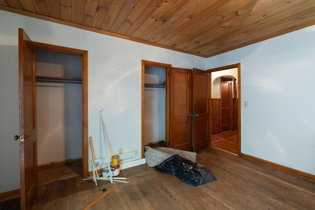 unfurnished bedroom with multiple closets, wood ceiling, and dark hardwood / wood-style floors