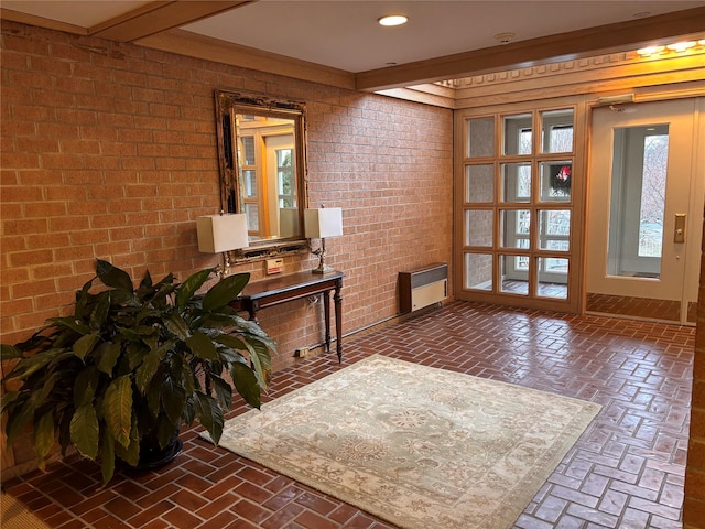 foyer with beam ceiling and brick wall