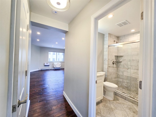 bathroom with toilet, hardwood / wood-style flooring, a shower with door, a baseboard heating unit, and vanity