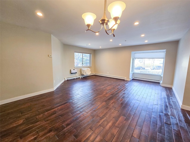 spare room with dark wood-type flooring, a baseboard radiator, a wealth of natural light, and a chandelier