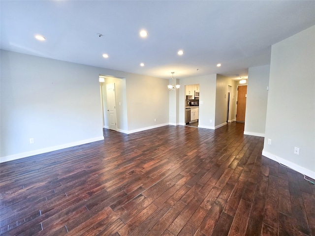 unfurnished living room with dark wood-type flooring and a notable chandelier