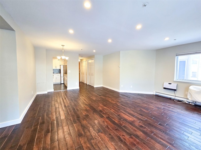 unfurnished living room featuring dark wood-type flooring, a baseboard radiator, and a notable chandelier