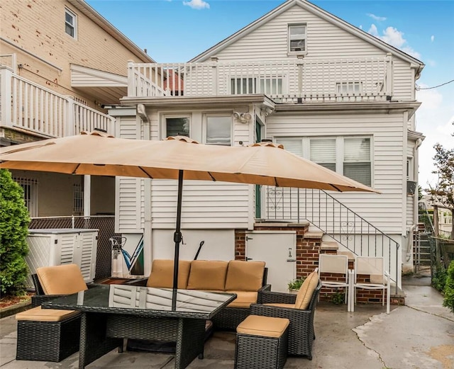 rear view of property with outdoor lounge area, a balcony, and a patio