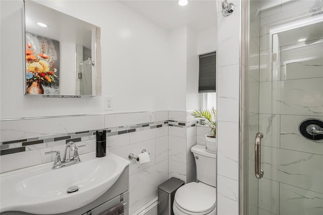 bathroom with vanity, toilet, tile walls, and a shower with shower door