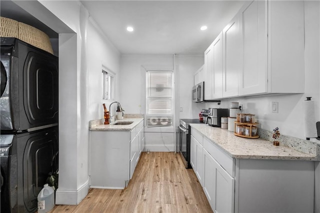 3026 Kingsland Ave, Bronx, NY 10469 - kitchen with stainless steel appliances, sink, light hardwood / wood-style flooring, stacked washer and clothes dryer, and white cabinetry
